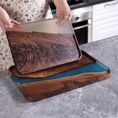 a woman is holding a cutting board on top of another cutting board