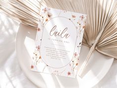 a white plate with an open book on top of it next to some fanned palm leaves