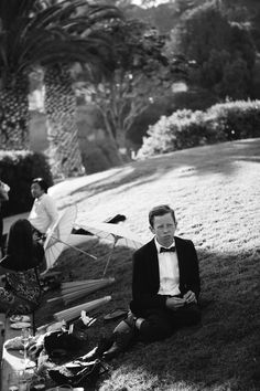 a man in a tuxedo sitting on the ground next to some kites