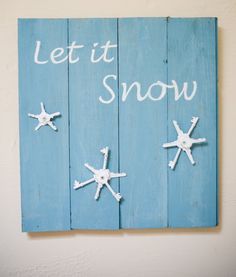 a wooden sign that says let it snow with starfishs on the bottom and words written in white