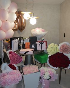 flowers and gifts are arranged on the table in front of balloons, gift boxes, and other items