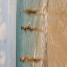 three people are swimming in the ocean with their feet up on the water's edge