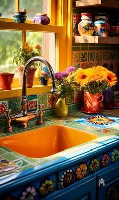 an orange sink sitting under a window next to a green counter top with flowers in vases on it