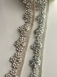 three different types of pearls and chains on a white surface with flowers in the background