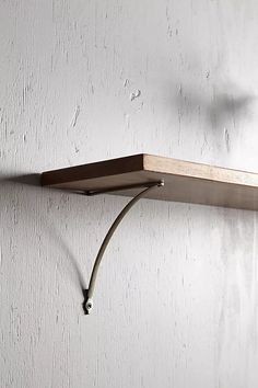 a wooden shelf mounted to the side of a white wall with a light on it