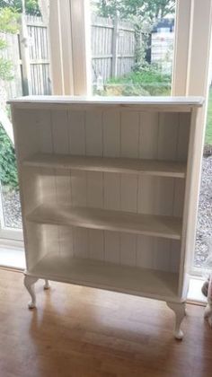 a white bookcase sitting on top of a hard wood floor next to a window