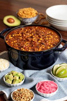 several bowls of food on a table with one bowl full of chili and the other two bowls filled with guacamole