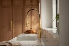 a kitchen with marble counter tops and gold faucet in the middle of it