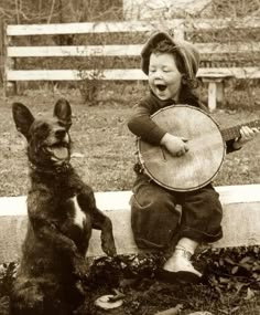 a little boy sitting next to a dog holding a guitar