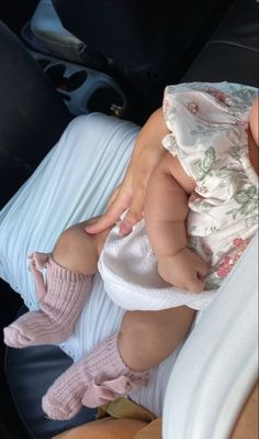 a baby is sitting in the back seat of a car with her feet on a pillow