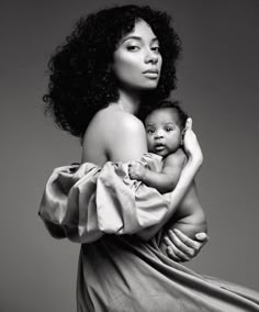 a woman holding a baby in her arms and posing for a black and white photo