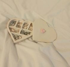 two heart shaped trays filled with rings on top of a white bed sheet next to each other