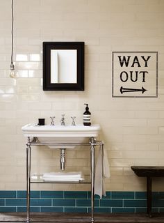 a bathroom sink sitting under a mirror next to a black and white tiled counter top