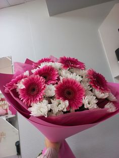 a bouquet of pink and white flowers in someone's hand