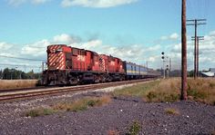 a red train traveling down tracks next to power lines and telephone poles on a cloudy day