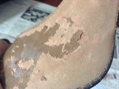 a person's foot with brown and white paint on it, next to newspaper