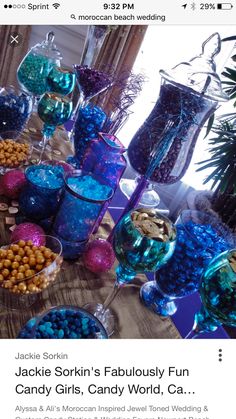 a table topped with lots of blue and purple candies next to vases filled with candy