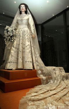 a mannequin wearing a wedding dress and veil on display in a glass case