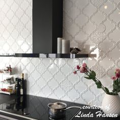 a vase with flowers sitting on top of a kitchen counter next to a pot filled with wine