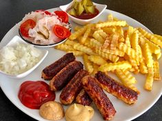 a white plate topped with french fries, ketchup and other foods on top of it