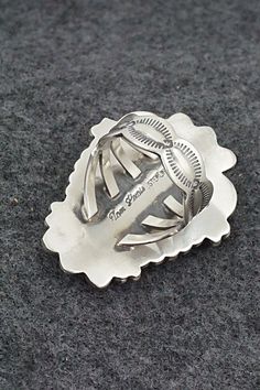 This White Buffalo and sterling silver ring was made by Navajo silversmith Tom Lewis. The back is signed and stamped sterling.Size: 9.25Length: 1 5/8"Width: 1 1/4"Free shipping on all orders! We ship with USPS and always include tracking. All orders ship within a day of payment.Returns are accepted up to 30 days after you receive your order. Just send us a message. Our shop offers cash back or store credit. The item must be returned in new condition. Silver Stamped Turquoise Ring Gift, Gift Silver Stamped Turquoise Ring, Silver Turquoise Concho Ring In Sterling Silver, Sterling Silver Stamped Turquoise Ring, Stamped Sterling Silver Turquoise Ring, Silver Engraved Southwestern Turquoise Ring, Engraved Silver Turquoise Ring In Southwestern Style, Engraved Silver Southwestern Turquoise Ring, Engraved Silver Turquoise Southwestern Ring