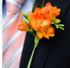 a boutonniere with orange flowers on the lapel of a man in a suit