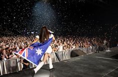 a woman holding an australian flag while standing on stage with confetti in the air