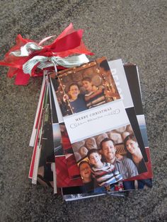 a stack of christmas cards sitting on top of a floor next to a red ribbon