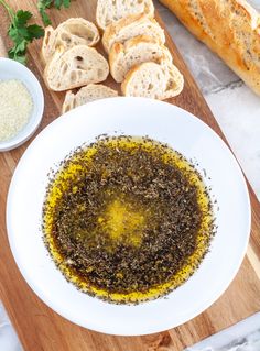 bread and olive oil on a wooden cutting board next to garlic bread, parmesan sprinkled with parsley