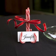 a candy cane with a name tag on it sitting next to a glass bowl and plate