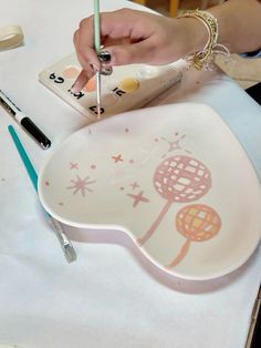 a person is drawing on a plate with a pencil