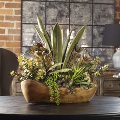 a wooden bowl filled with plants on top of a table