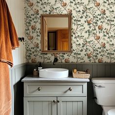 a bathroom with a sink, toilet and wall papered in floral designs on the walls