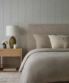 a bedroom with a bed, night stand and two vases on the side table