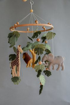 a mobile with animals and plants hanging from it's sides on a gray wall