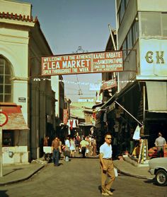 a man walking down the middle of a street in front of buildings with signs on them