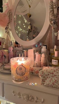 a white dresser topped with lots of different types of candles and bottles next to a mirror