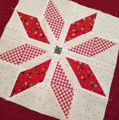 a red and white quilted table topper on a checkered table cloth with an ornament in the center