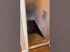 an open door leading to a bathroom with a toilet on the wall and wood floors