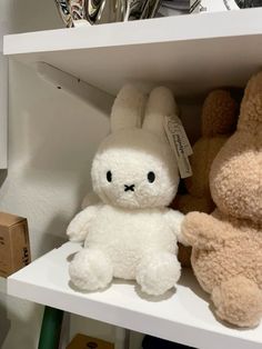 two stuffed animals sitting on top of a white shelf