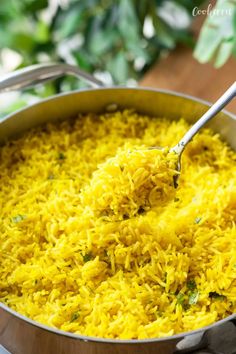 a pot full of yellow rice with a spoon in it