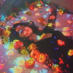 a woman laying on top of a bed covered in colorful lights and confetti