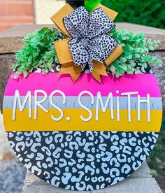 a sign that says mrs smith on it with leopard print and green plants in the center