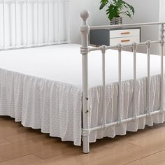 a white bed with a wooden headboard and foot board in a room next to a window