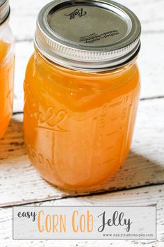 two jars filled with orange liquid sitting on top of a white wooden table next to each other