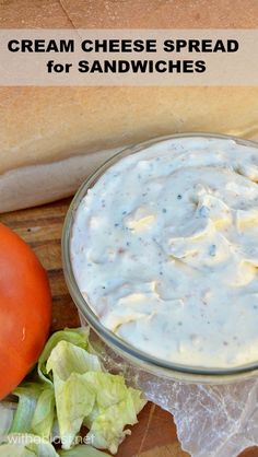 a bowl of cream cheese spread with lettuce next to a tomato and bread roll