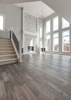 an empty living room with wood floors and large windows