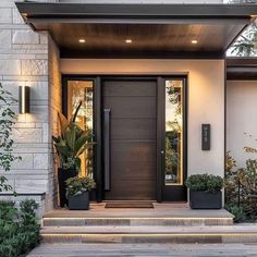 the front entrance to a modern home with potted plants