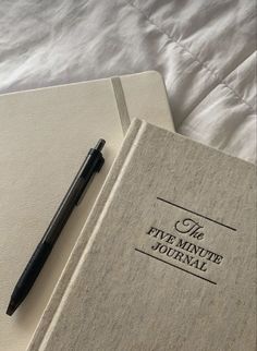 a pen sitting on top of a book next to an open notebook with the title'the five minute journal '