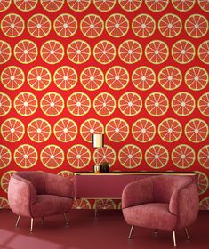 two chairs sitting in front of a wall with orange slices on it and a lamp next to them